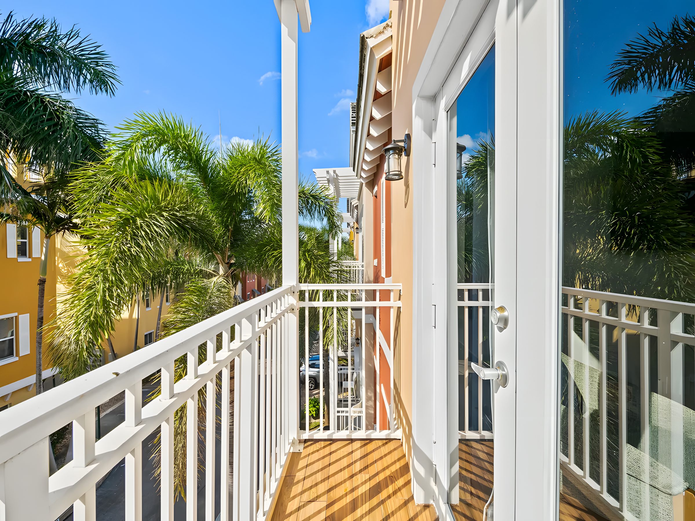 A white balcony looking over the palms and the neighbouring townhomes.